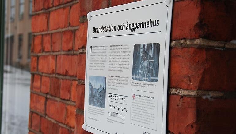 Emaljskylt på tegelvägg.