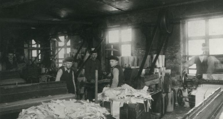 Två män och två pojkar står vid farnersvarvarna inne i fabriken. 